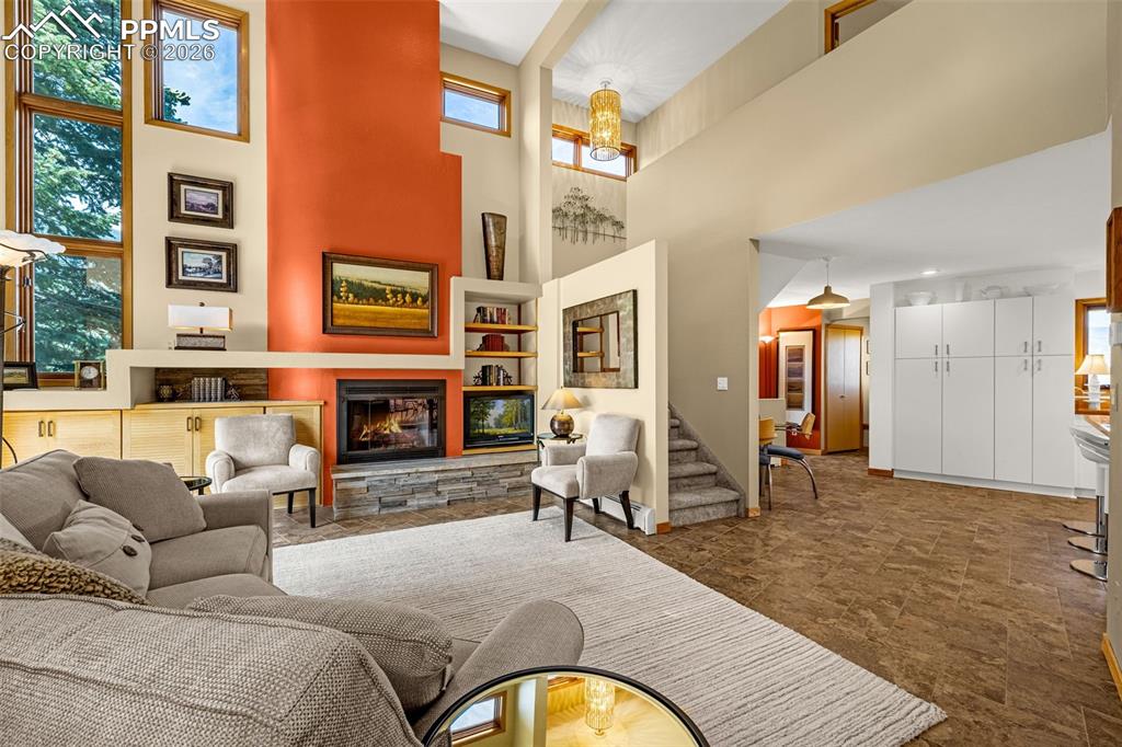 Living room featuring a fireplace, a high ceiling, and a chandelier