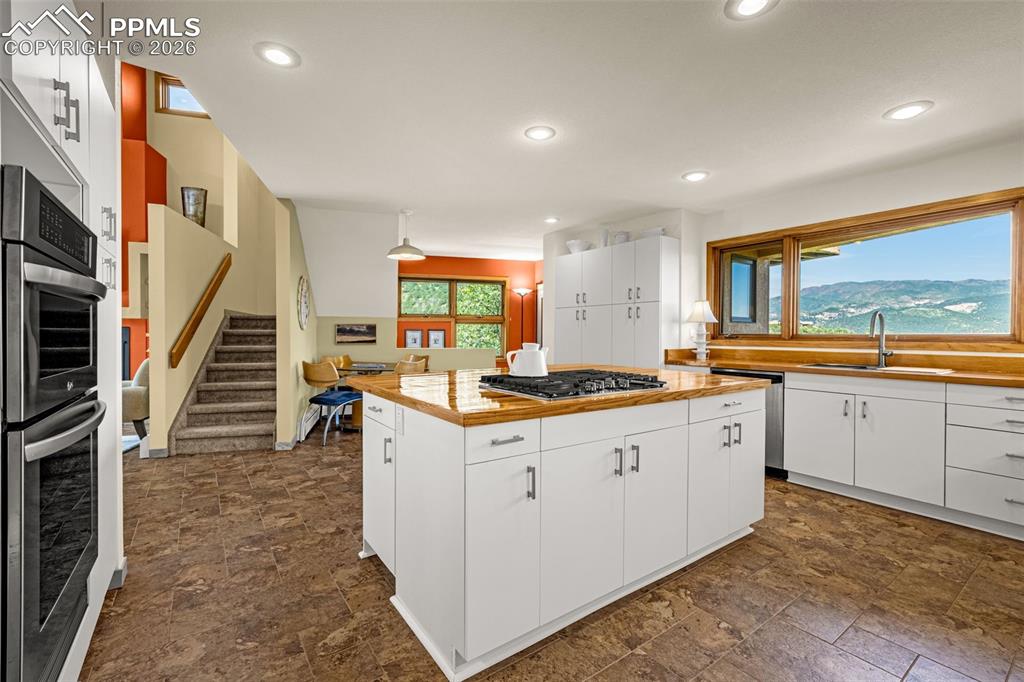 Kitchen with stone finish flooring, white cabinets, stainless steel appliances, and a center island