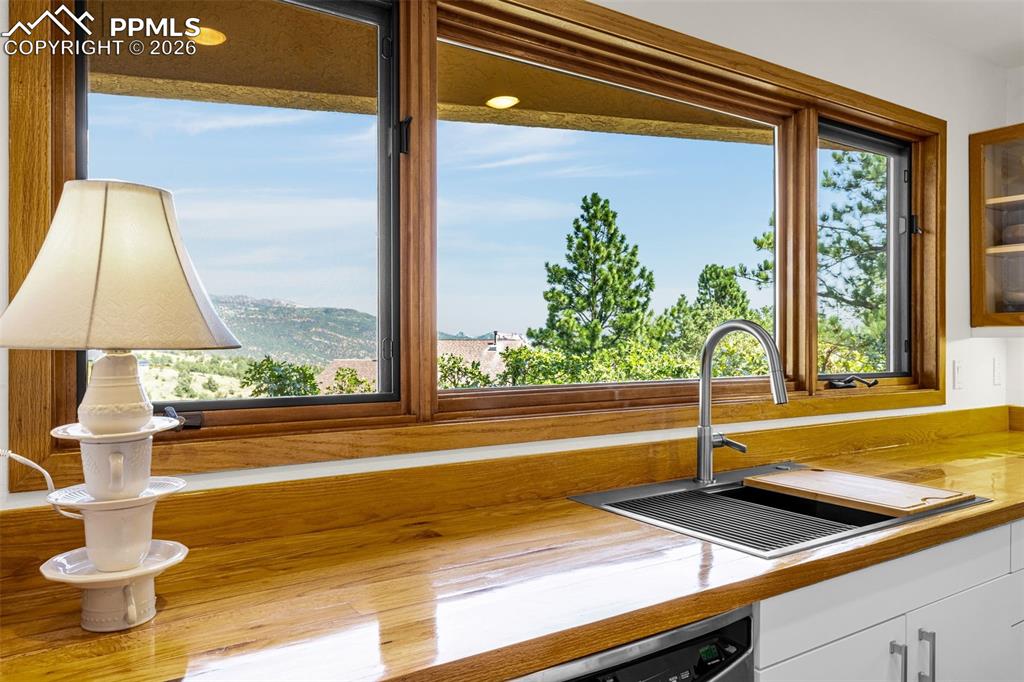 Kitchen view of white cabinets, stainless steel dishwasher, and glass fronted cabinets