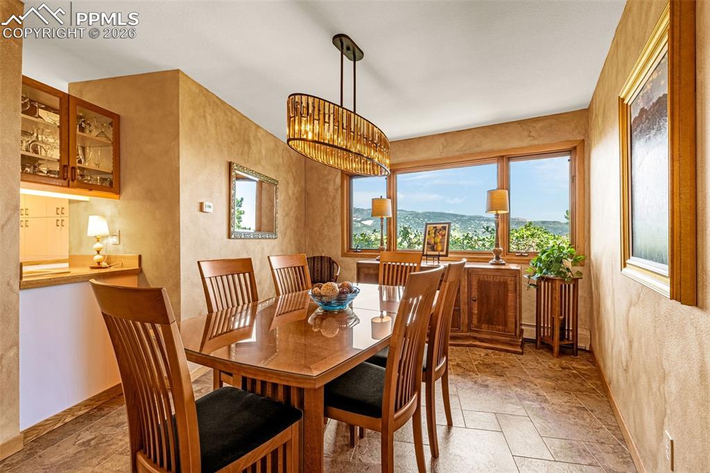Dining area featuring stone tile floors, a textured wall, and hanging lights
