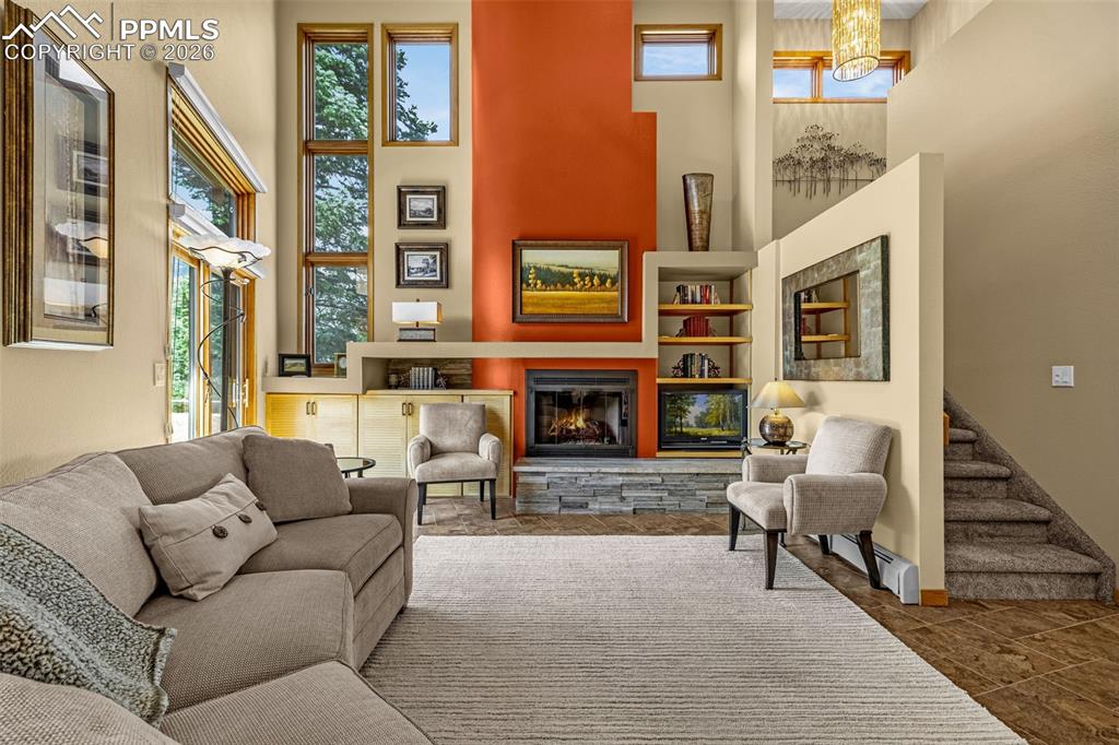 Living area featuring a high ceiling and a stone fireplace