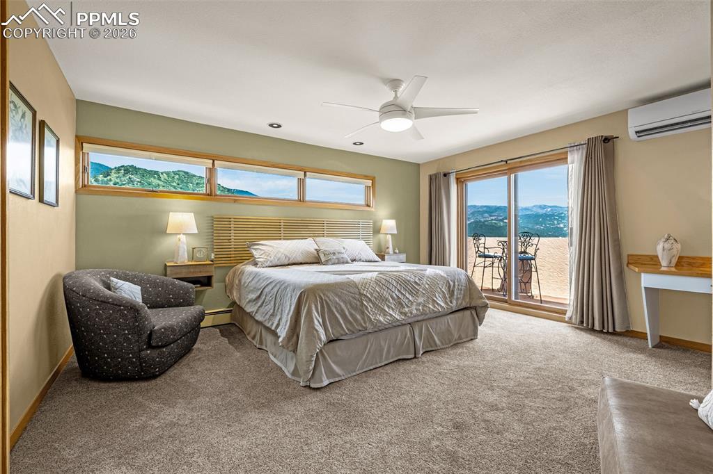 Carpeted bedroom with a mountain view, multiple windows, and ceiling fan