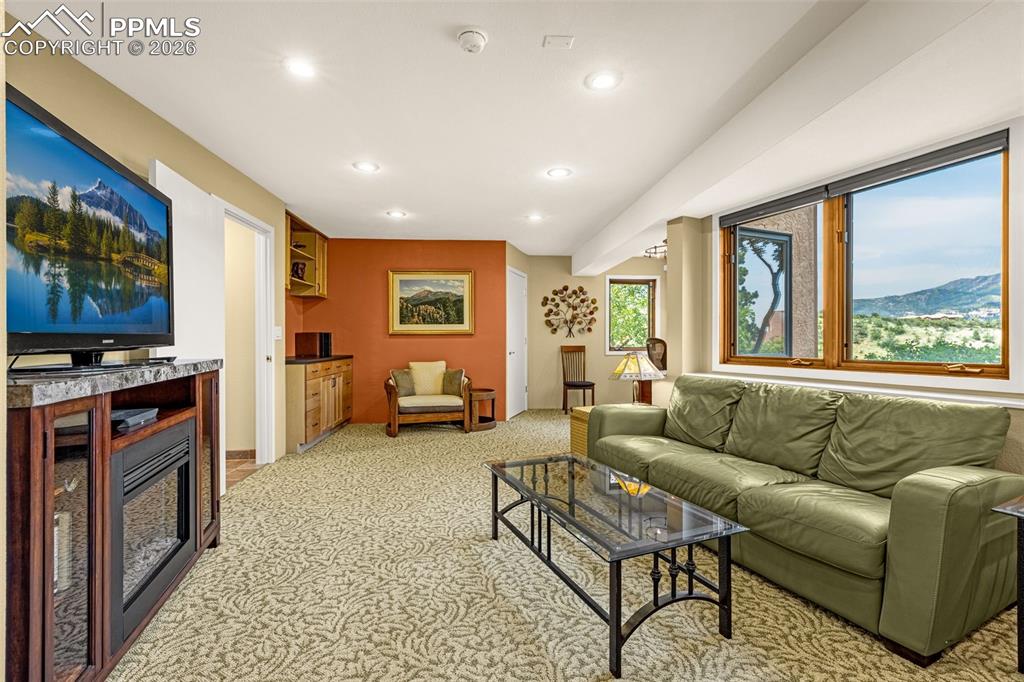 Finished basement, garden level windows. Living room with recessed lighting, light colored carpet, a mountain view, and a fireplace