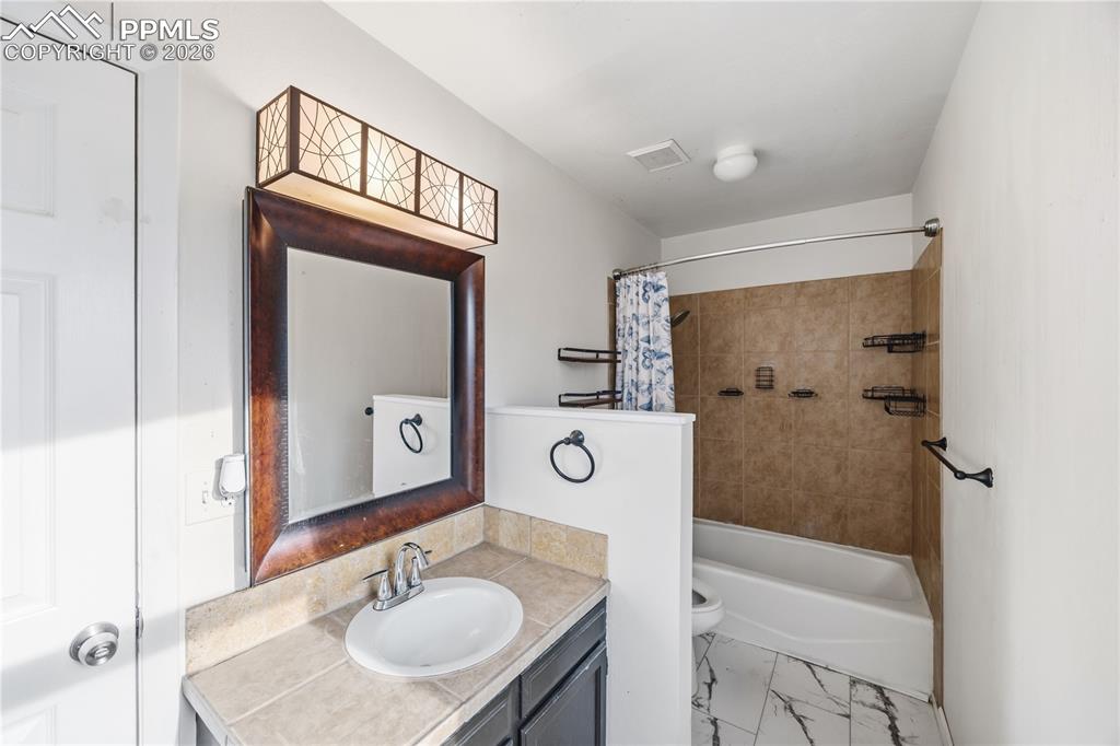 The primary bathroom features a vanity, framed mirror, and tiled tub/shower.