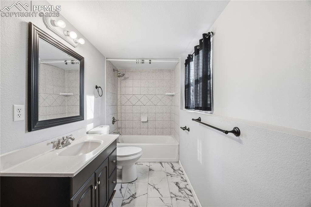 Lower level full batrhoom with vanity, framed mirror, and tiled tub/shower.