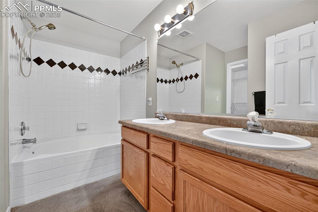 Bathroom featuring double vanity, tiled shower / bath combo.