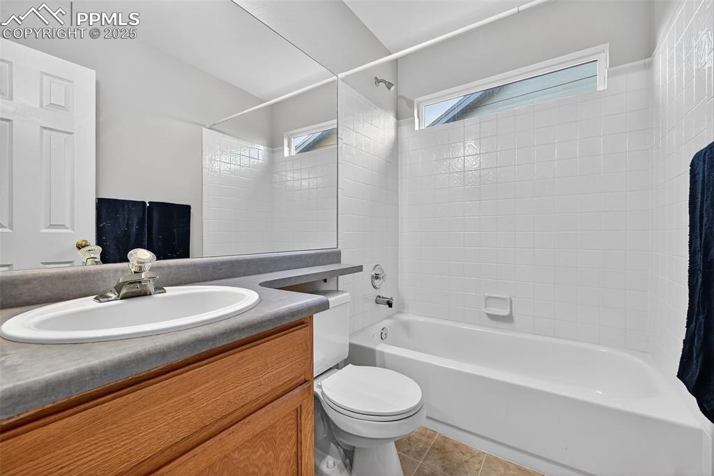 Full bath is next to second bedroom on main level with vanity, shower / bath combination, and light tile patterned flooring. Window makes in nice and bright!