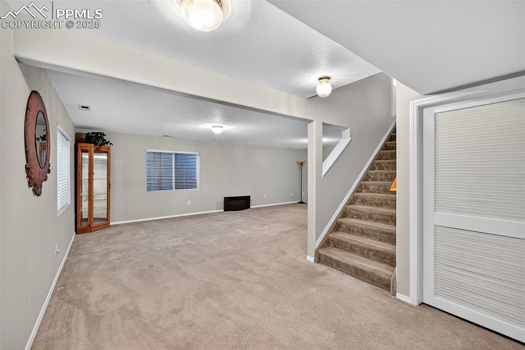 Spacious Basement featuring light colored carpet and stairway