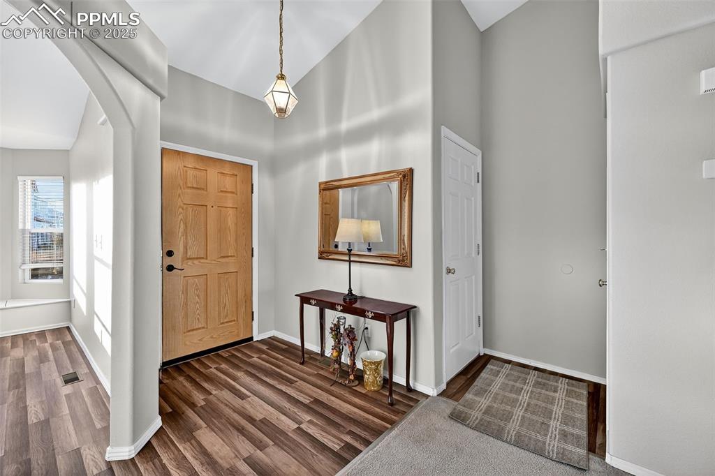 Entrance foyer featuring arched walkways and dark wood pergo-style flooring