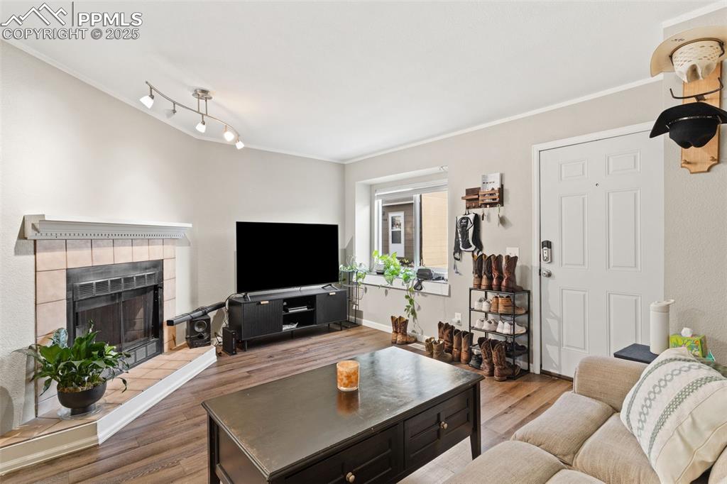 Living room with a tile fireplace, ornamental molding, and wood finished floors