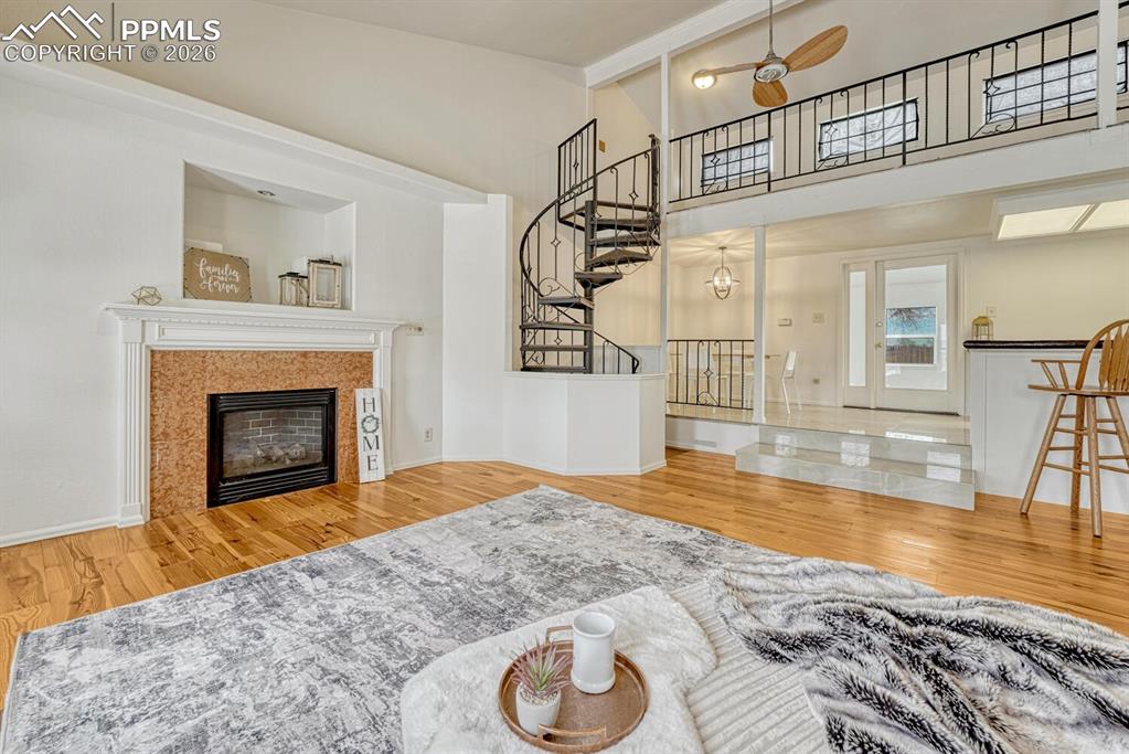 Living room with view of spiral staircase to loft, wet bar and dining area with walkout to sun room