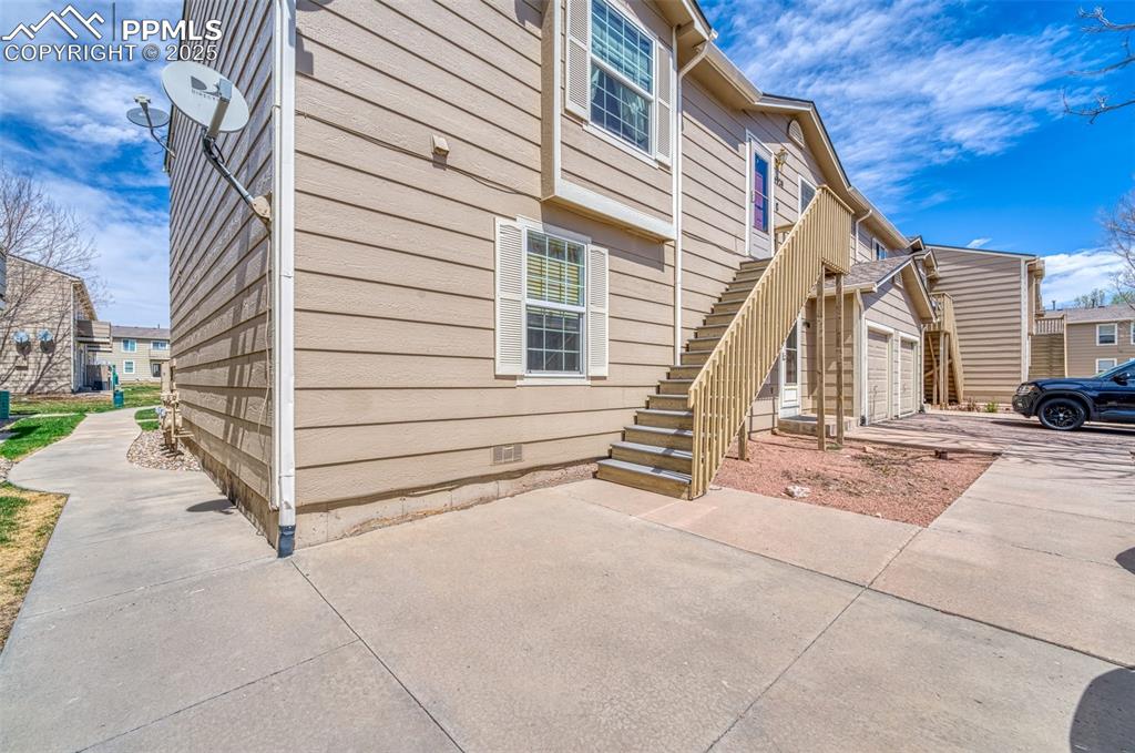 View of side of home featuring a garage, crawl space, stairway, concrete driveway, and a residential view