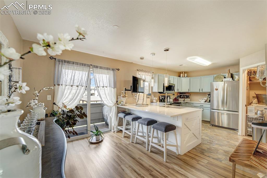 Kitchen featuring a breakfast bar, light wood-type flooring, a peninsula, light countertops, and stainless steel appliances