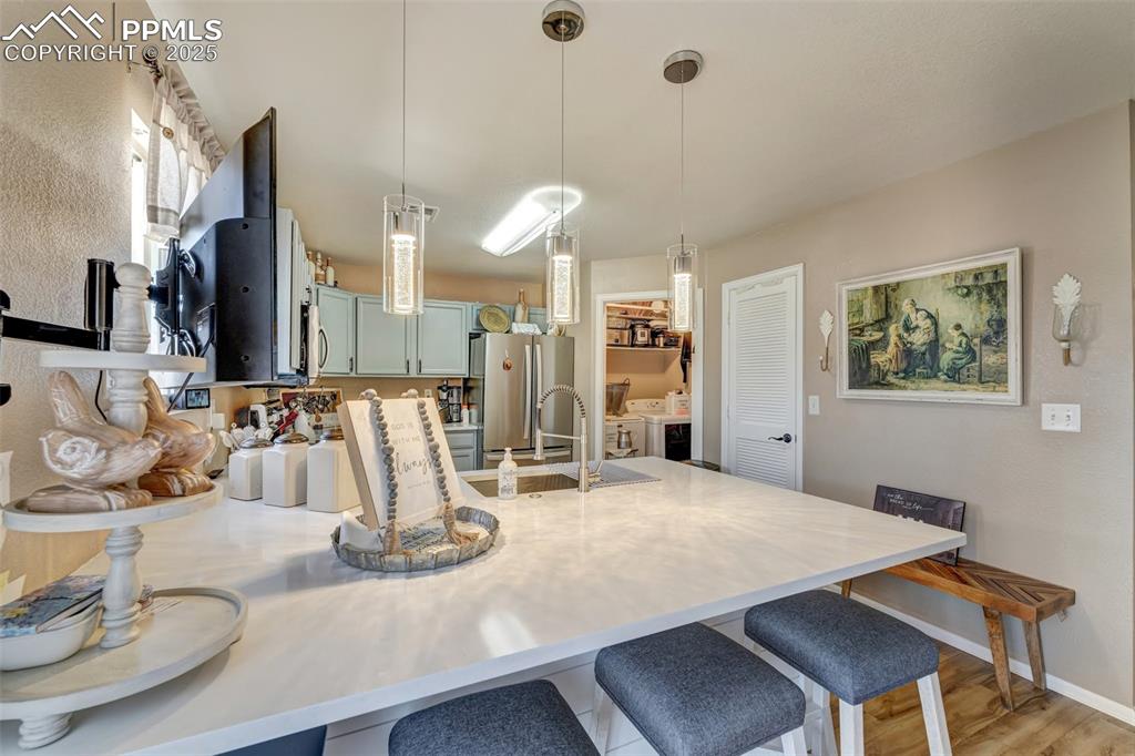 Kitchen with a sink, light countertops, appliances with stainless steel finishes, a kitchen breakfast bar, and a peninsula
