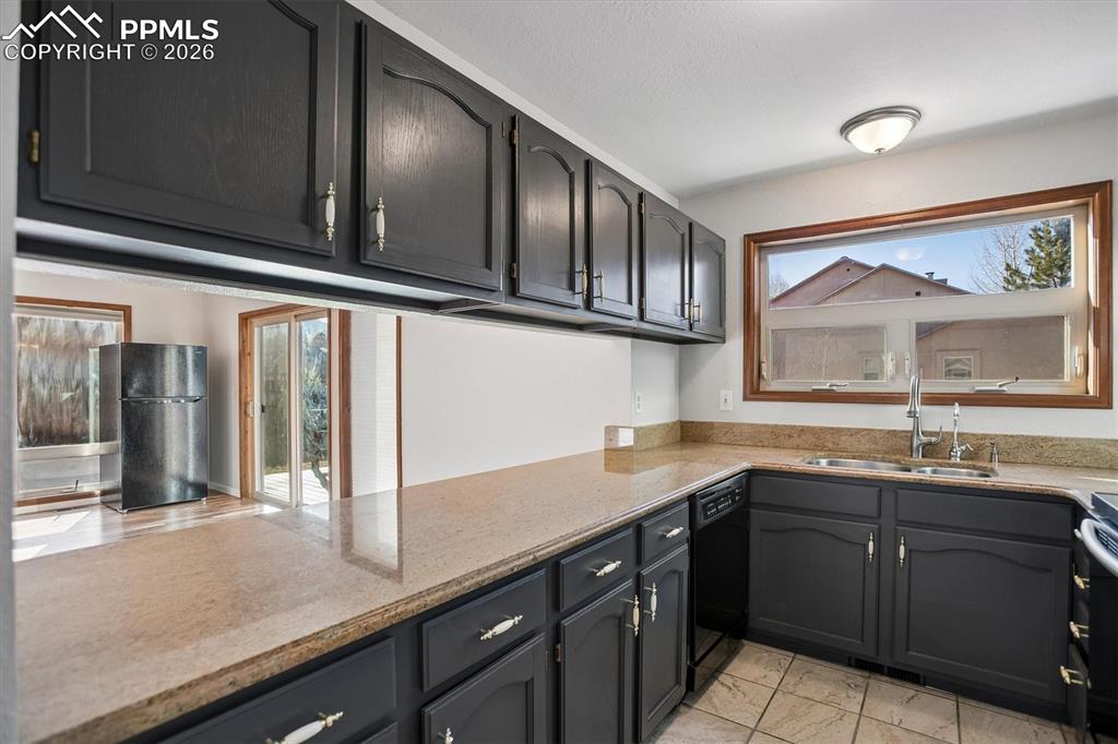 Kitchen with light stone countertops and black appliances