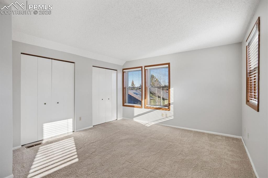 Unfurnished bedroom with multiple closets and light carpet