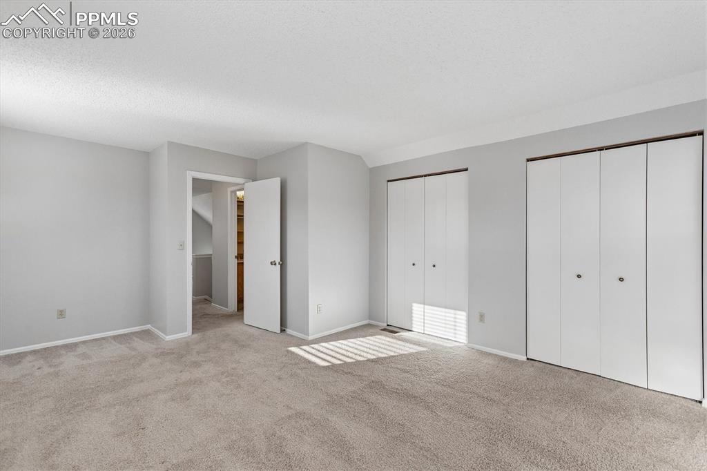 Unfurnished bedroom with two closets and light carpet