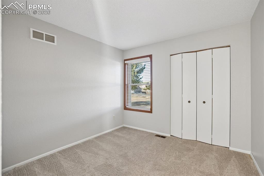Unfurnished bedroom with light colored carpet, a closet, and a textured ceiling
