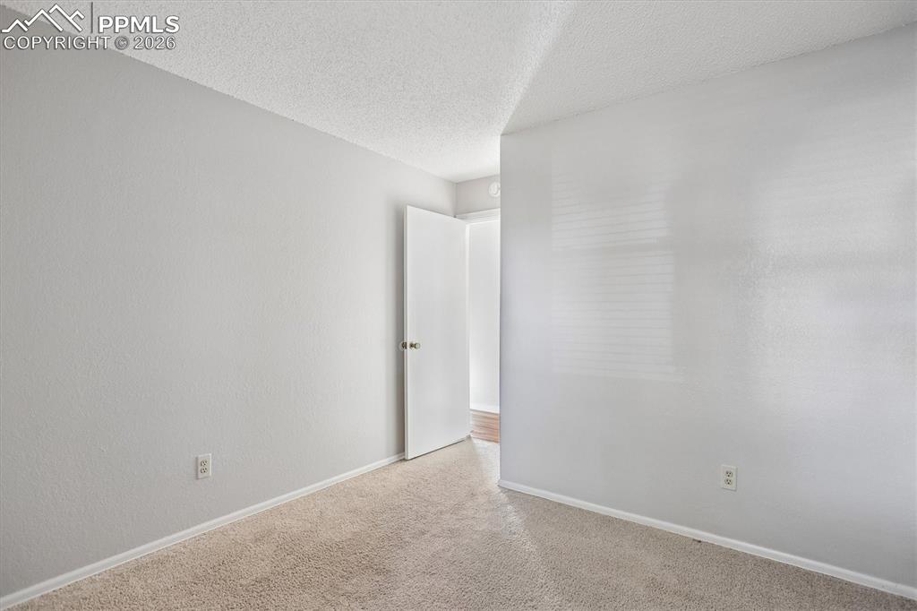 Carpeted empty room with baseboards and a textured ceiling