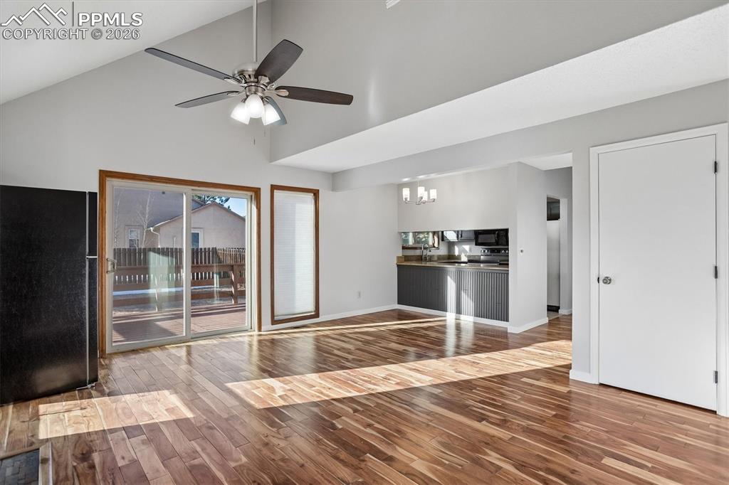 Unfurnished living room with dark wood finished floors, a chandelier, lofted ceiling, and ceiling fan
