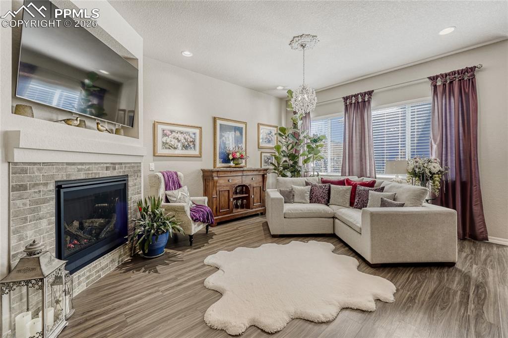 Living room with a fireplace, LVP floors, and a chandelier