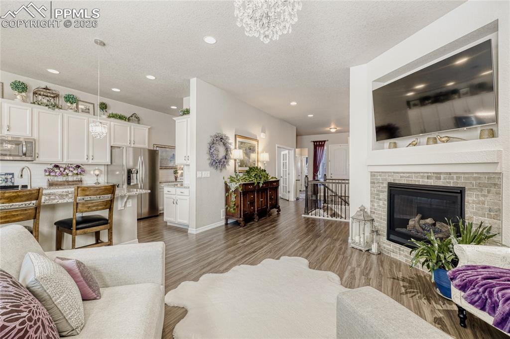 Living area featuring hanging lights, a brick fireplace, dark wood-style flooring, and a textured ceiling