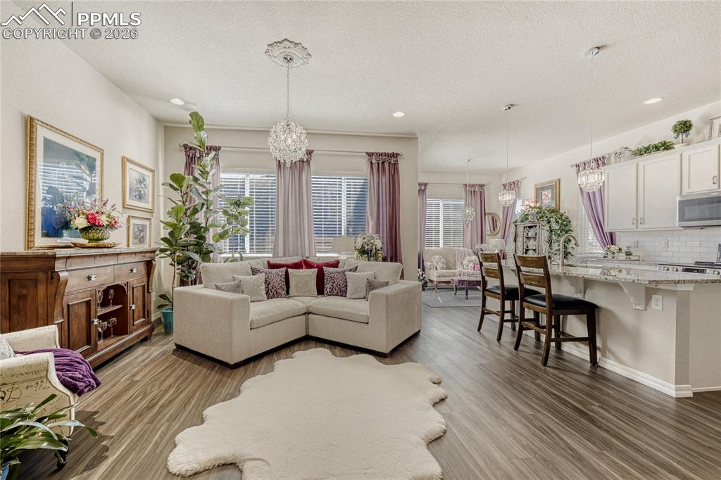 Living room with a chandelier, healthy amount of natural light, dark wood-style flooring, and a textured ceiling
