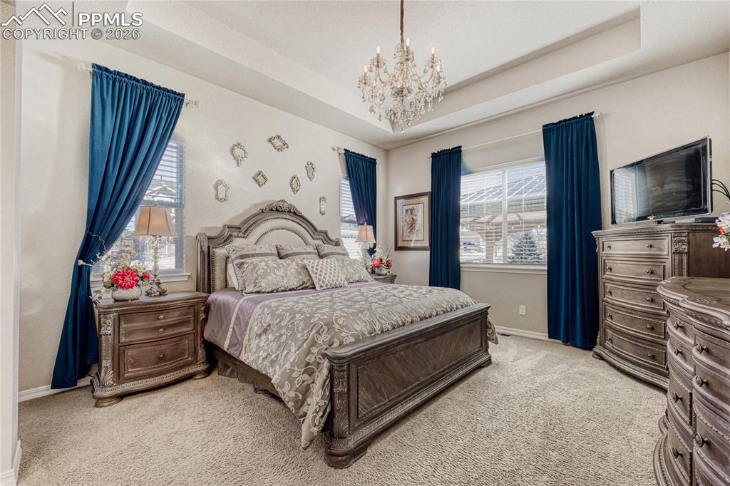Master Bedroom with  tray ceiling, chandelier and light carpet
