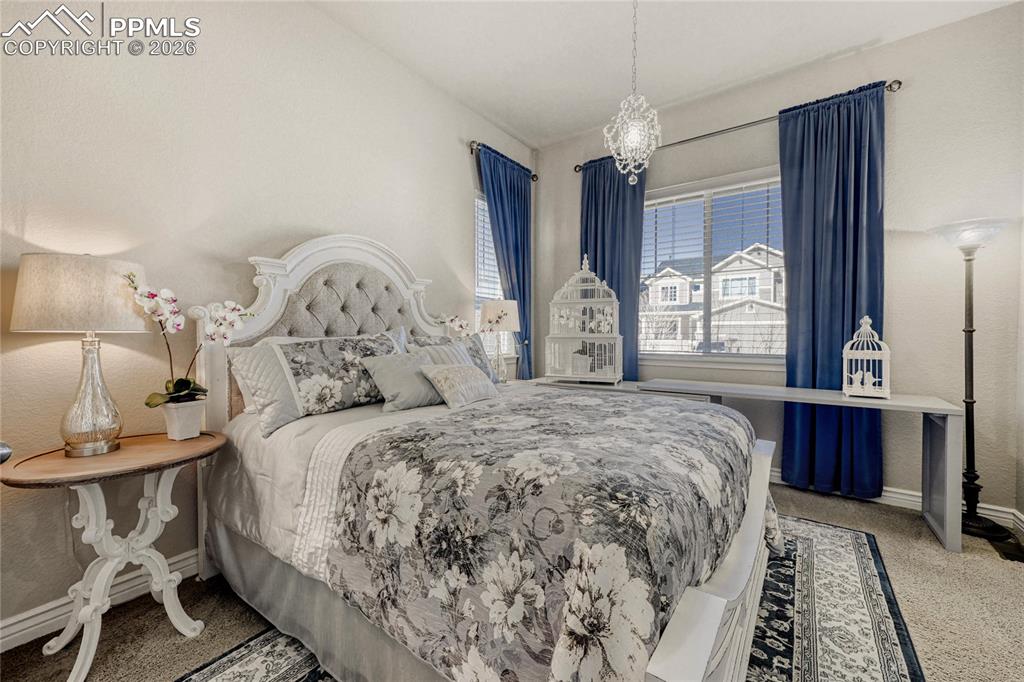 Guest Bedroom featuring light colored carpet chandelier and walk-in closet 
