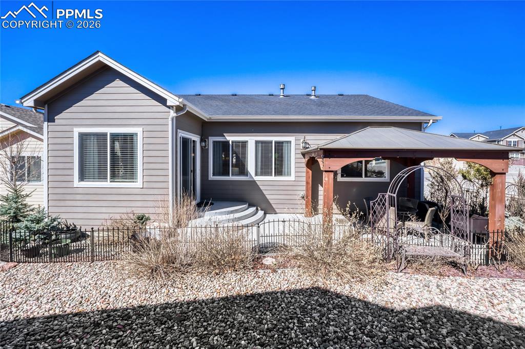 Rear view of property with a gazebo, a patio, and a shingled roof