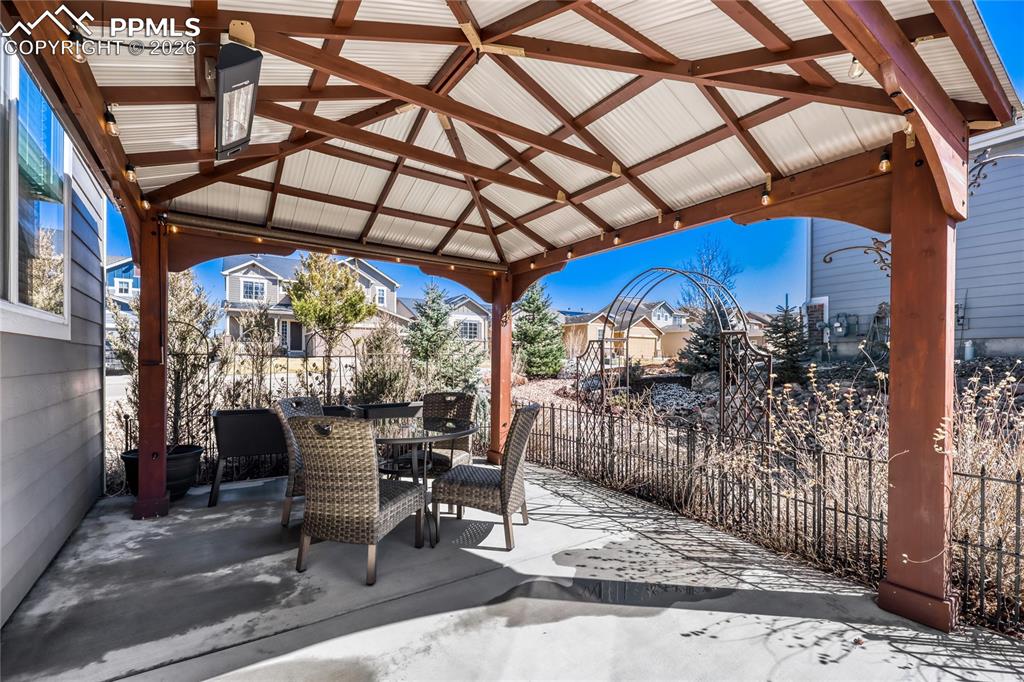Fenced backyard featuring a patio, a residential view, outdoor dining area, and a gazebo