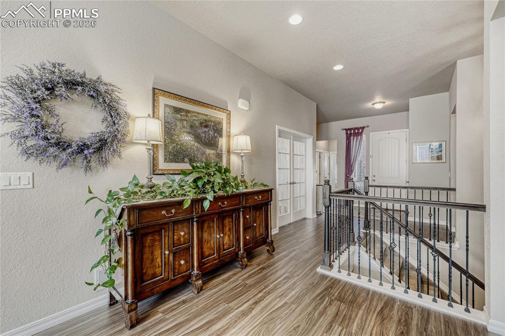 Hall with an upstairs landing with LVP floors and recessed lighting