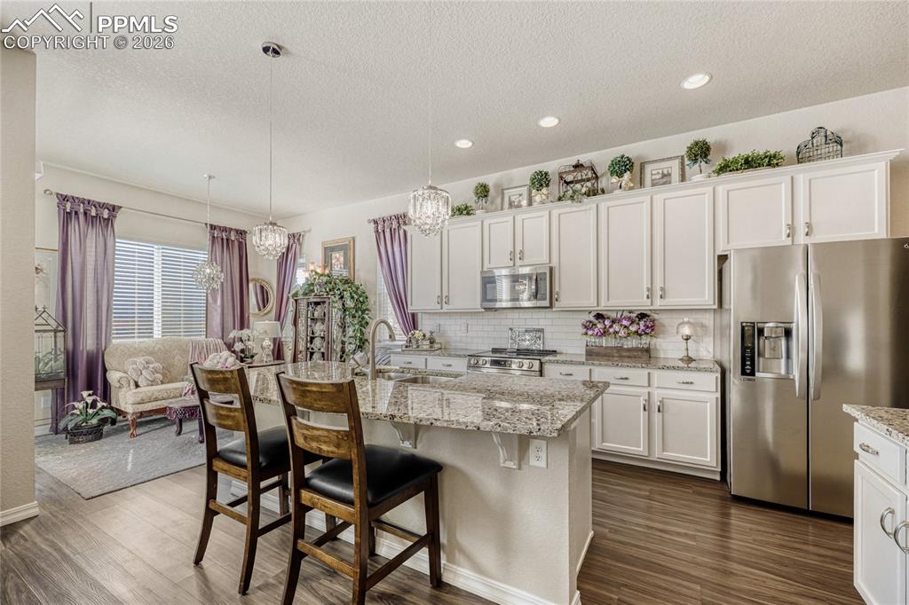 Kitchen featuring stainless steel appliances, white cabinetry, a breakfast bar 