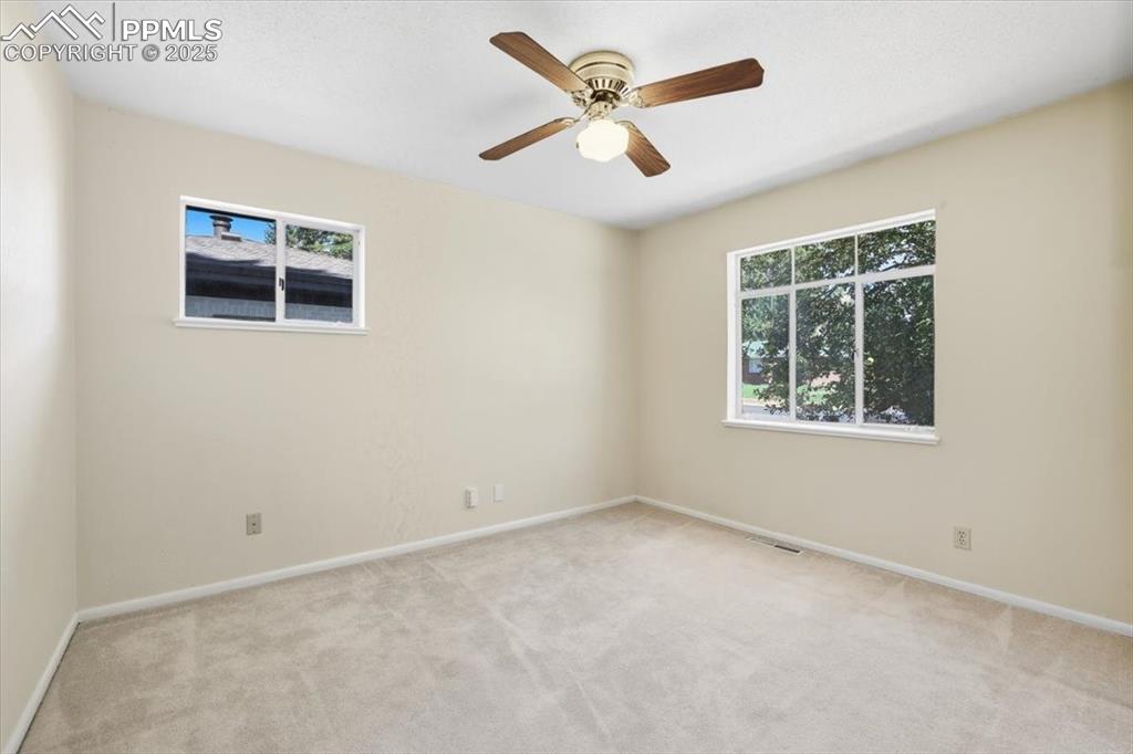 Empty room featuring light colored carpet and a ceiling fan