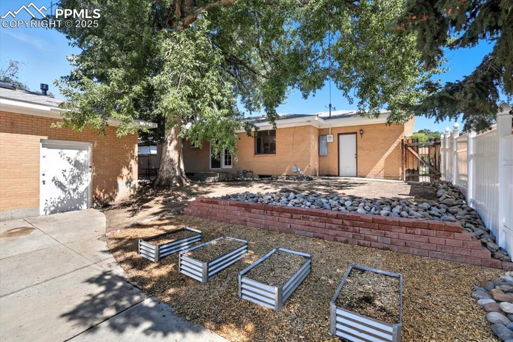 Back of property featuring a vegetable garden, a patio, and brick siding