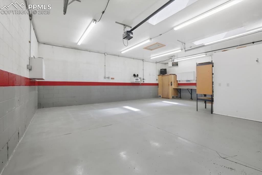 Garage featuring a garage door opener and concrete block wall