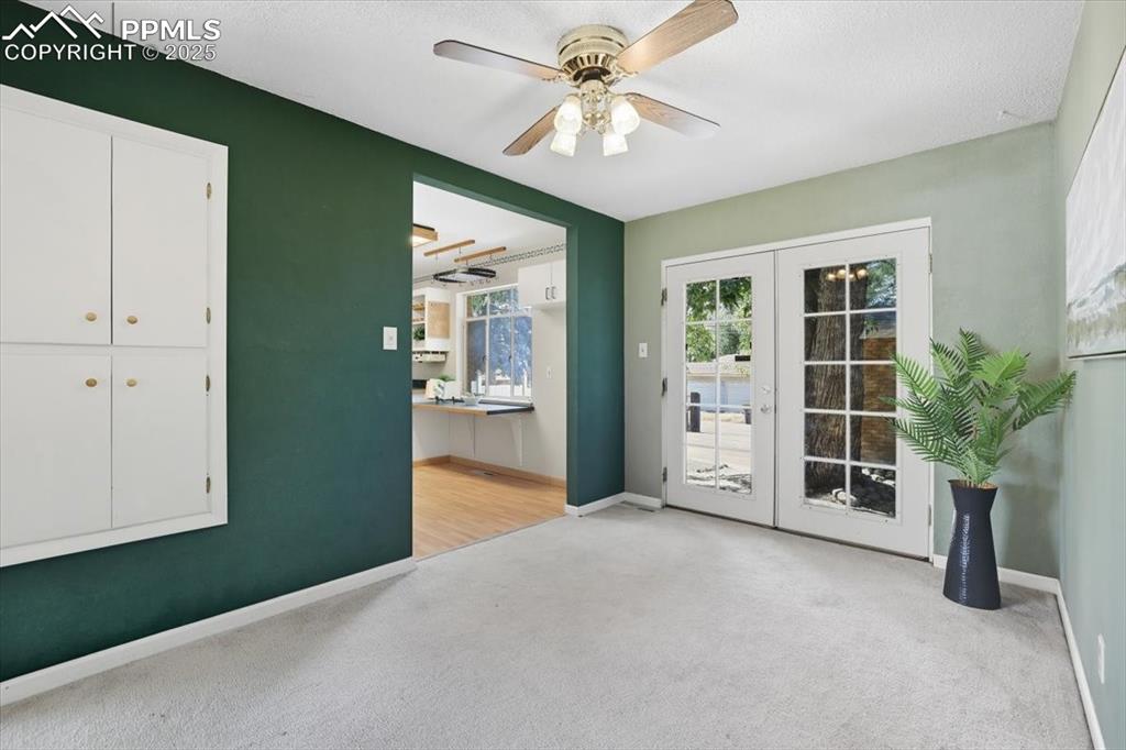 Doorway featuring french doors, carpet floors, and a ceiling fan