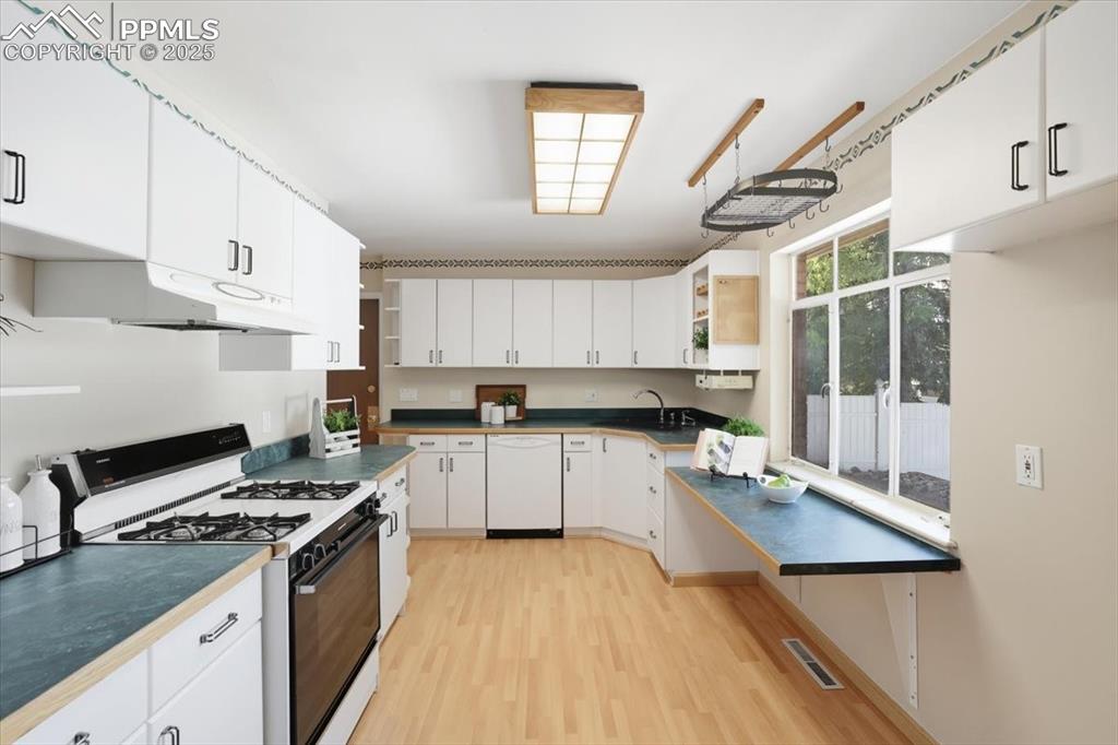 Kitchen with white appliances, white cabinetry, open shelves, and light wood-style flooring