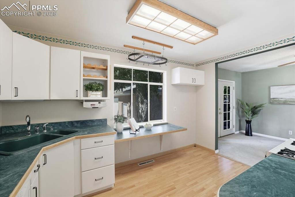 Kitchen featuring dark countertops, white cabinetry, light wood-style flooring, and open shelves