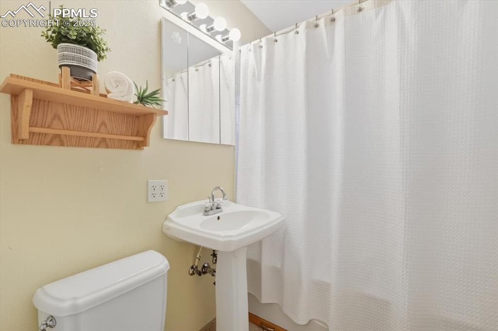 Full bathroom featuring toilet and shower / bath combination with curtain