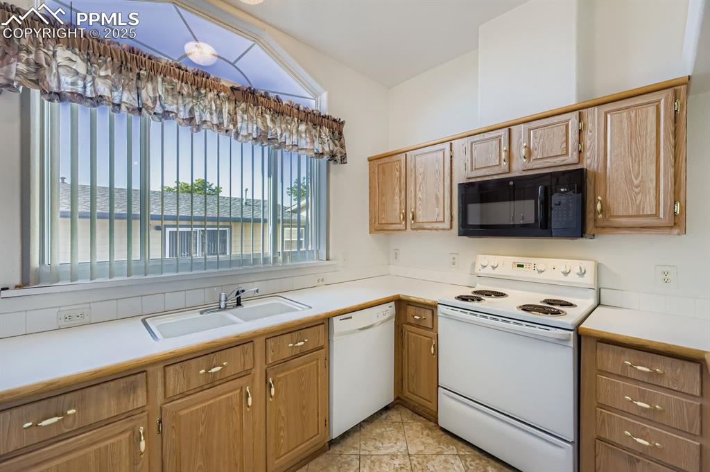 Kitchen featuring white appliances, light countertops, and light tile patterned floors