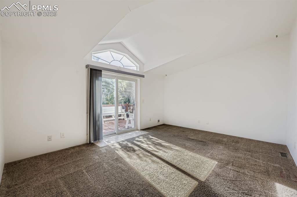Carpeted empty room featuring high vaulted ceiling