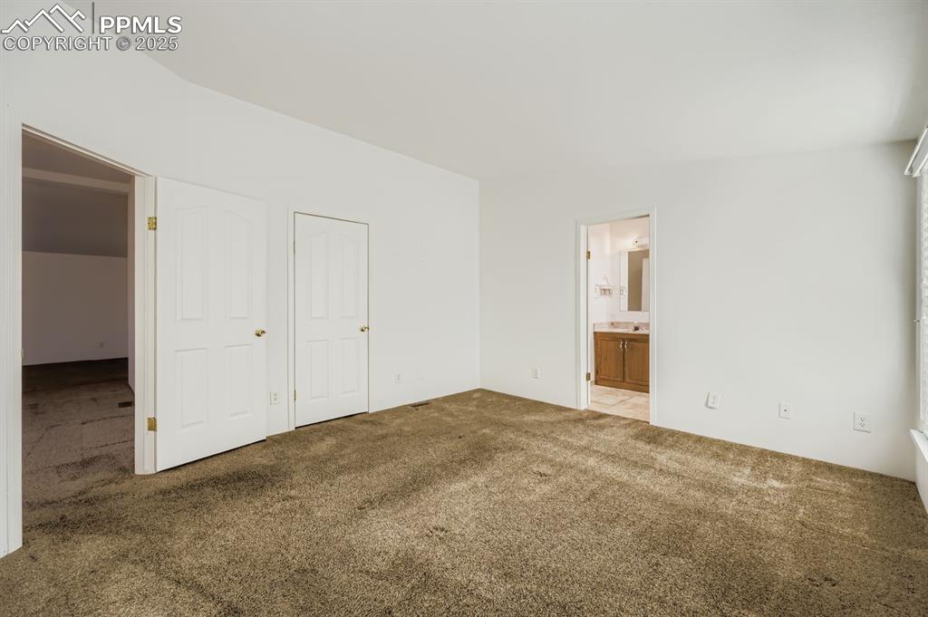 Unfurnished bedroom with carpet floors and ensuite bath