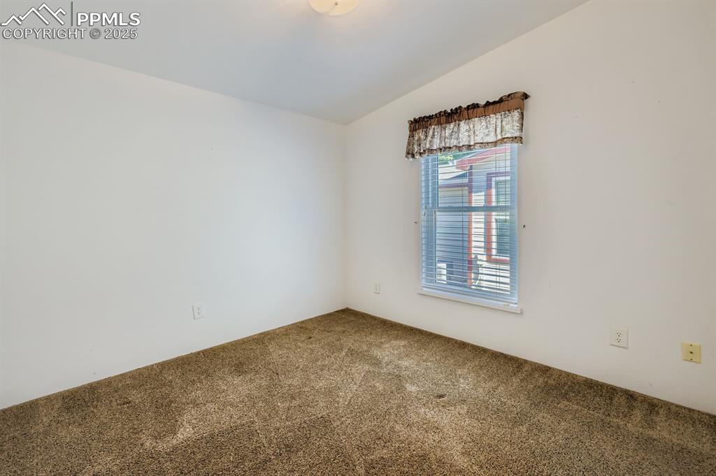 Carpeted empty room featuring lofted ceiling