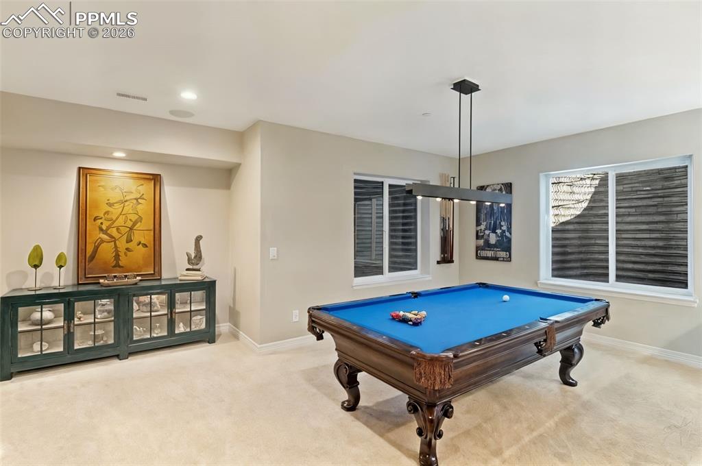 Dedicated recreation space easily houses a billiards table, bathed in natural light from oversized window wells that eliminate any traditional basement feel
