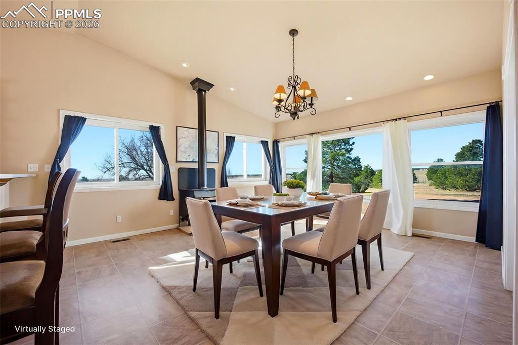 Dining area with lofted ceiling, hanging lights, and a wood stove