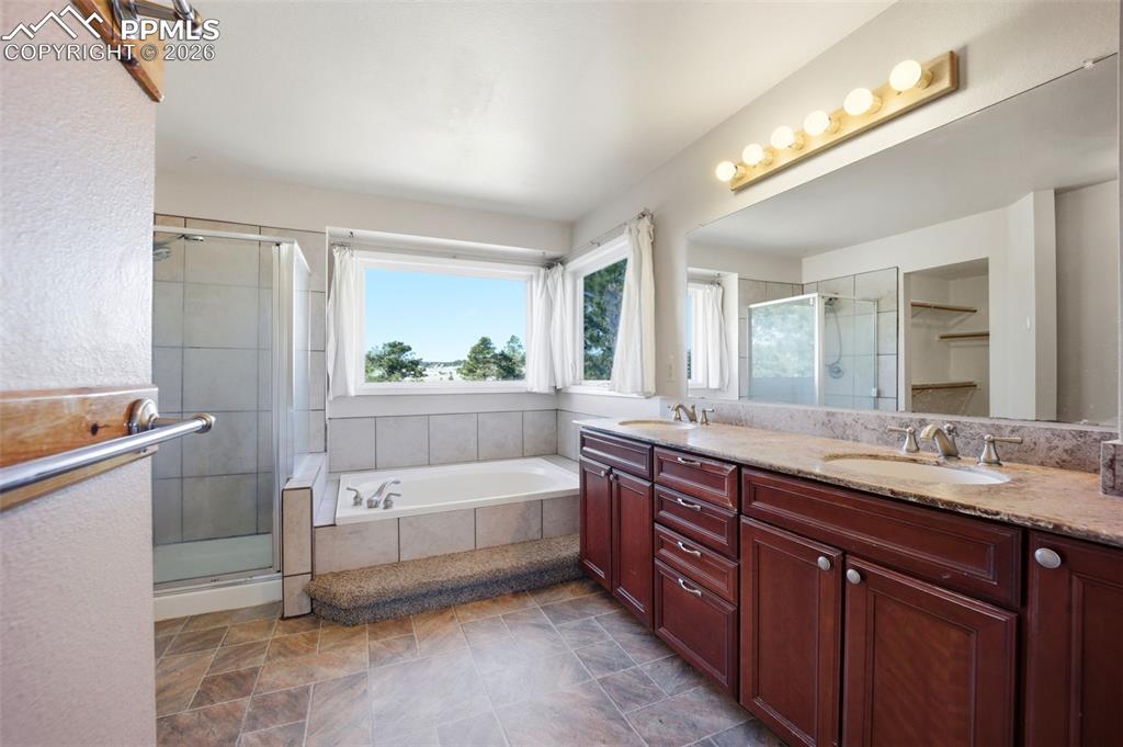 Primary bathroom featuring double vanity, a shower stall, and a garden tub