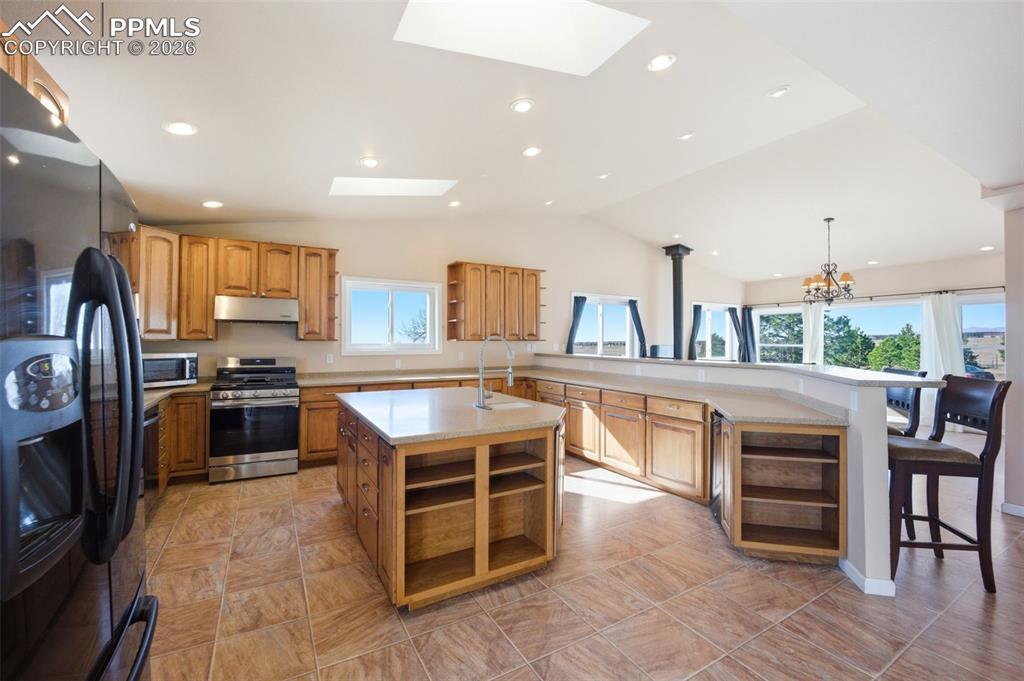Kitchen with high end wood cabinets, Corian countertops, 2 skylights, large island with room for a second sink, and a kitchen breakfast bar
