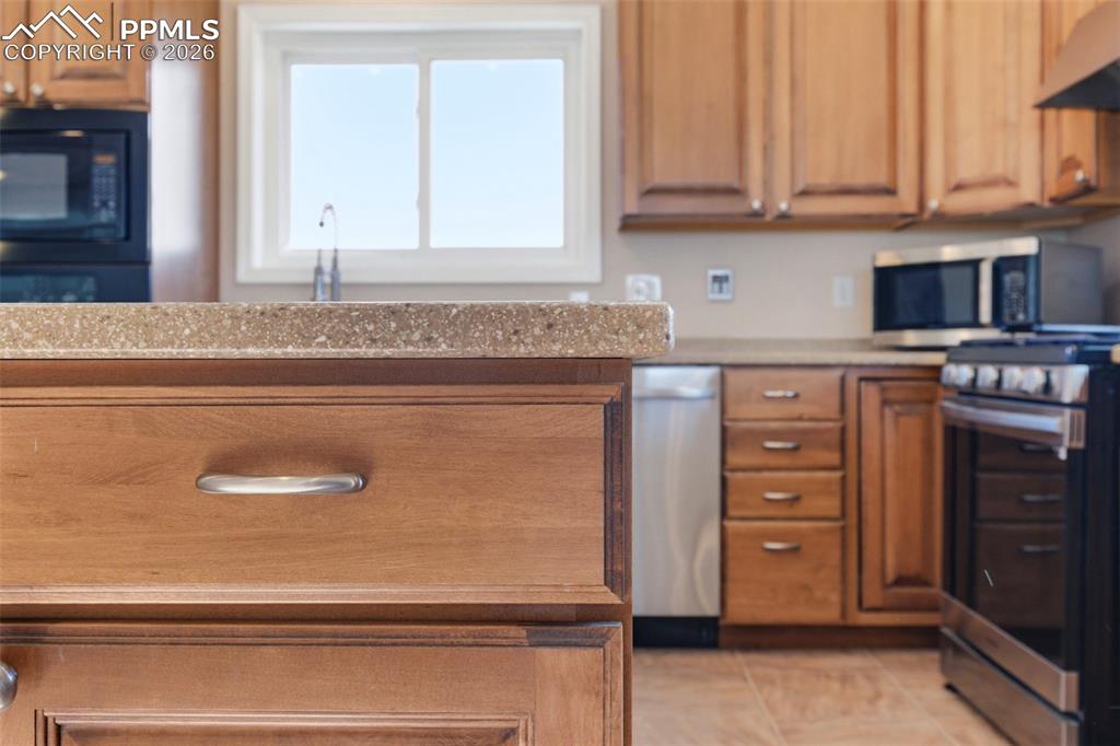 Kitchen with wood finish cabinets, Corian countertops, and light tile patterned floors