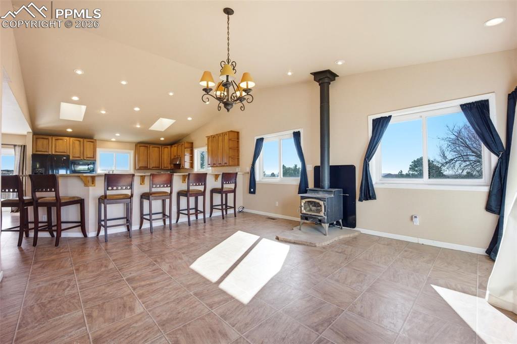 Dining area with lofted ceiling, hanging lights, and a wood stove